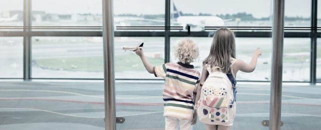 Two children looking out at airplanes from an airport window, representing family visitation and child custody arrangements during holidays in Texas.